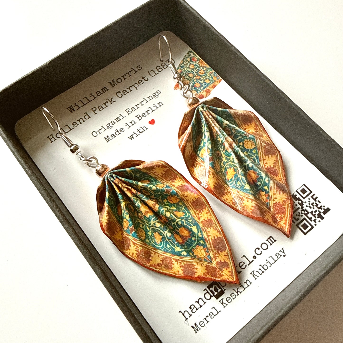 Pair of origami-style earrings in a box with a card detailing the brand and design inspiration.