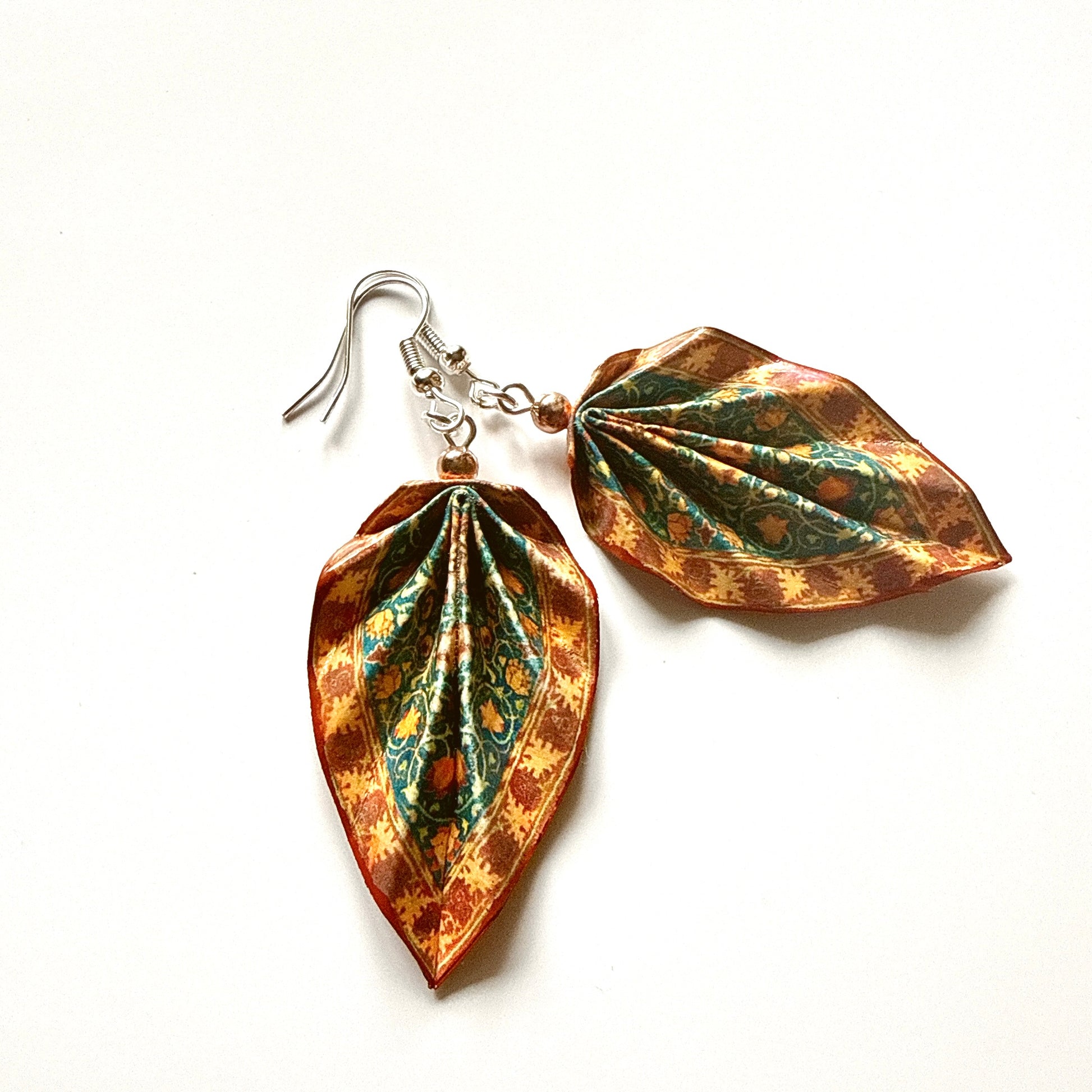 Pair of leaf-shaped earrings with a copper and green finish on a white background