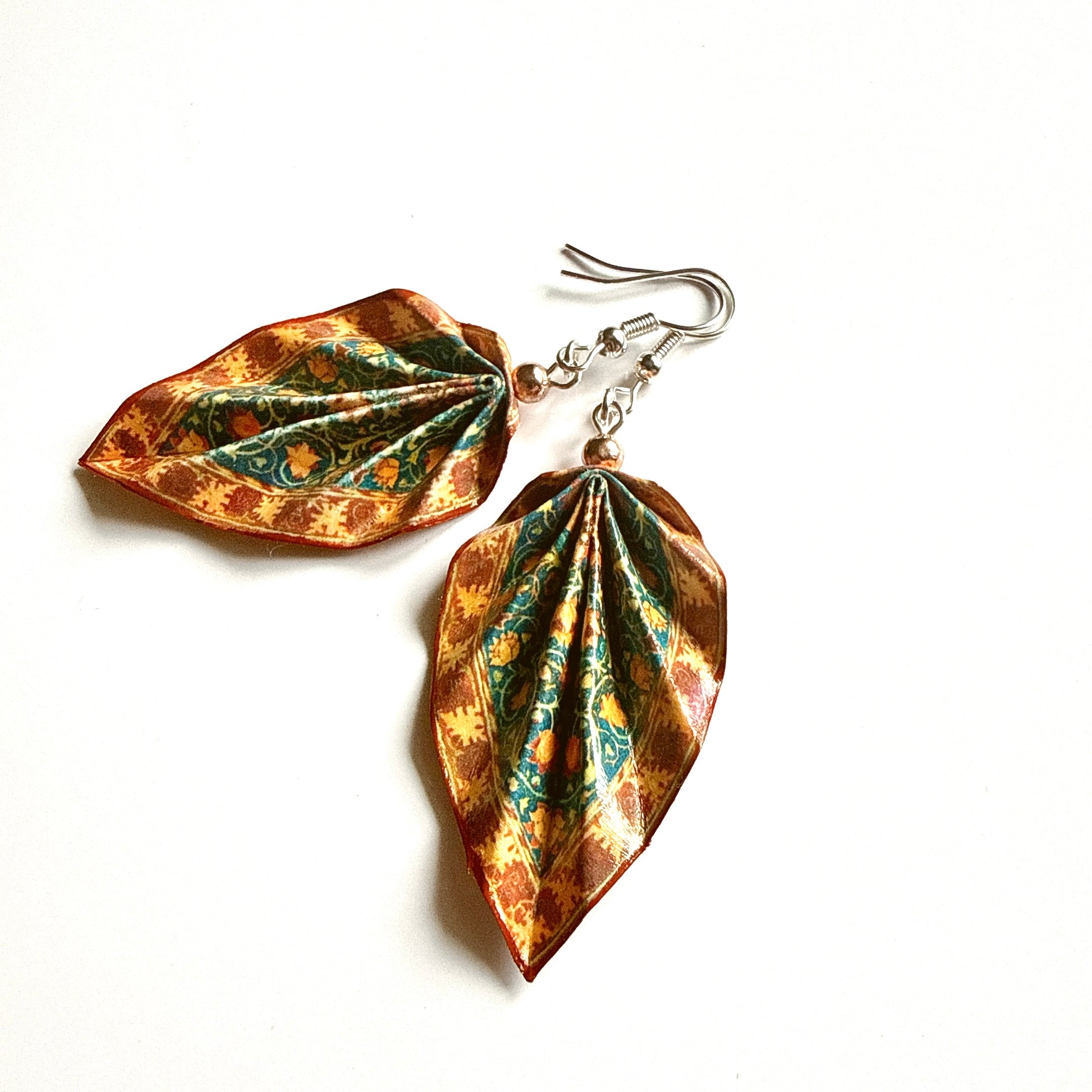 Pair of leaf-shaped earrings with a metallic finish on a white background