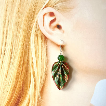 Close-up of a person wearing a green and red leaf-shaped earring.