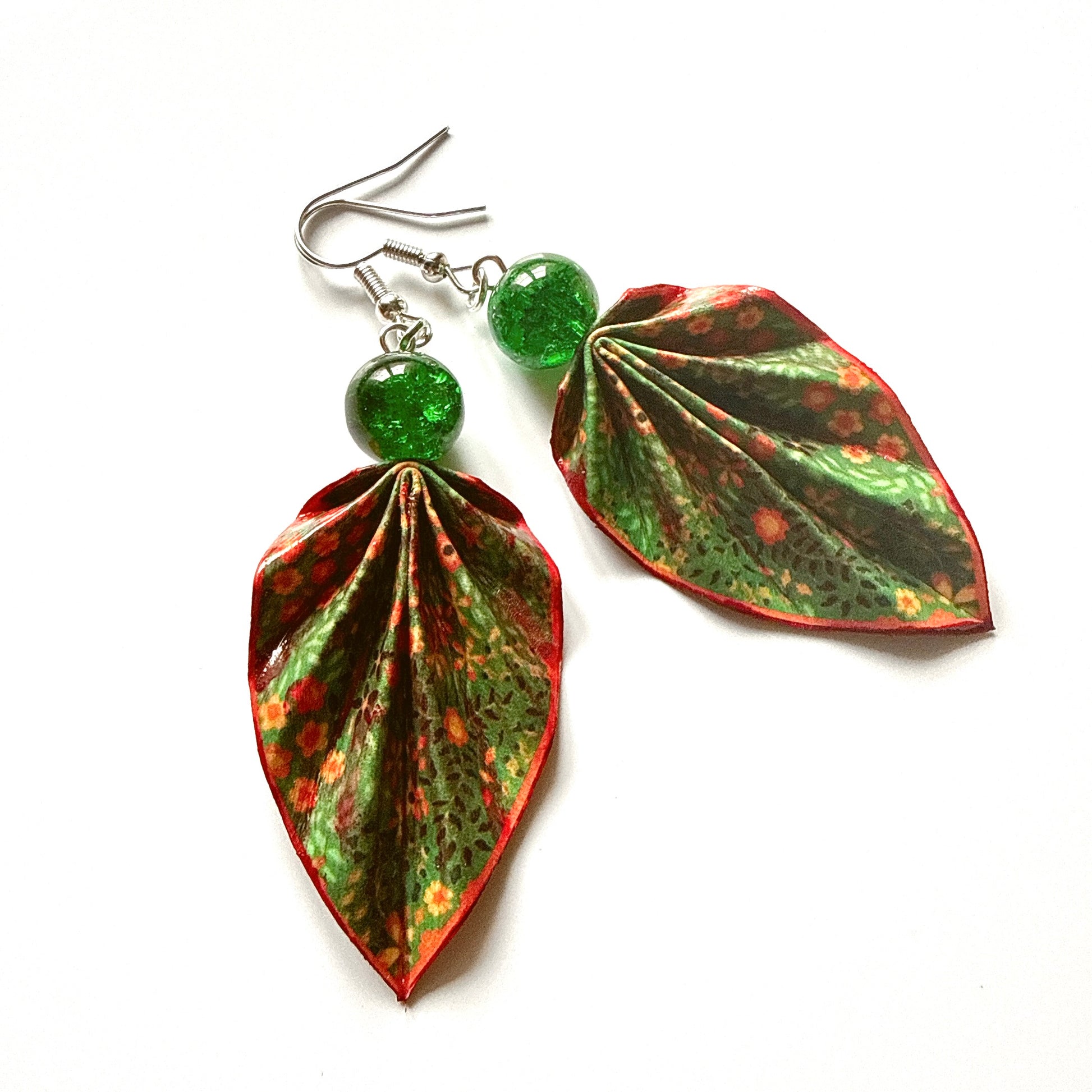 Pair of leaf-shaped earrings with green and red patterns on a white background