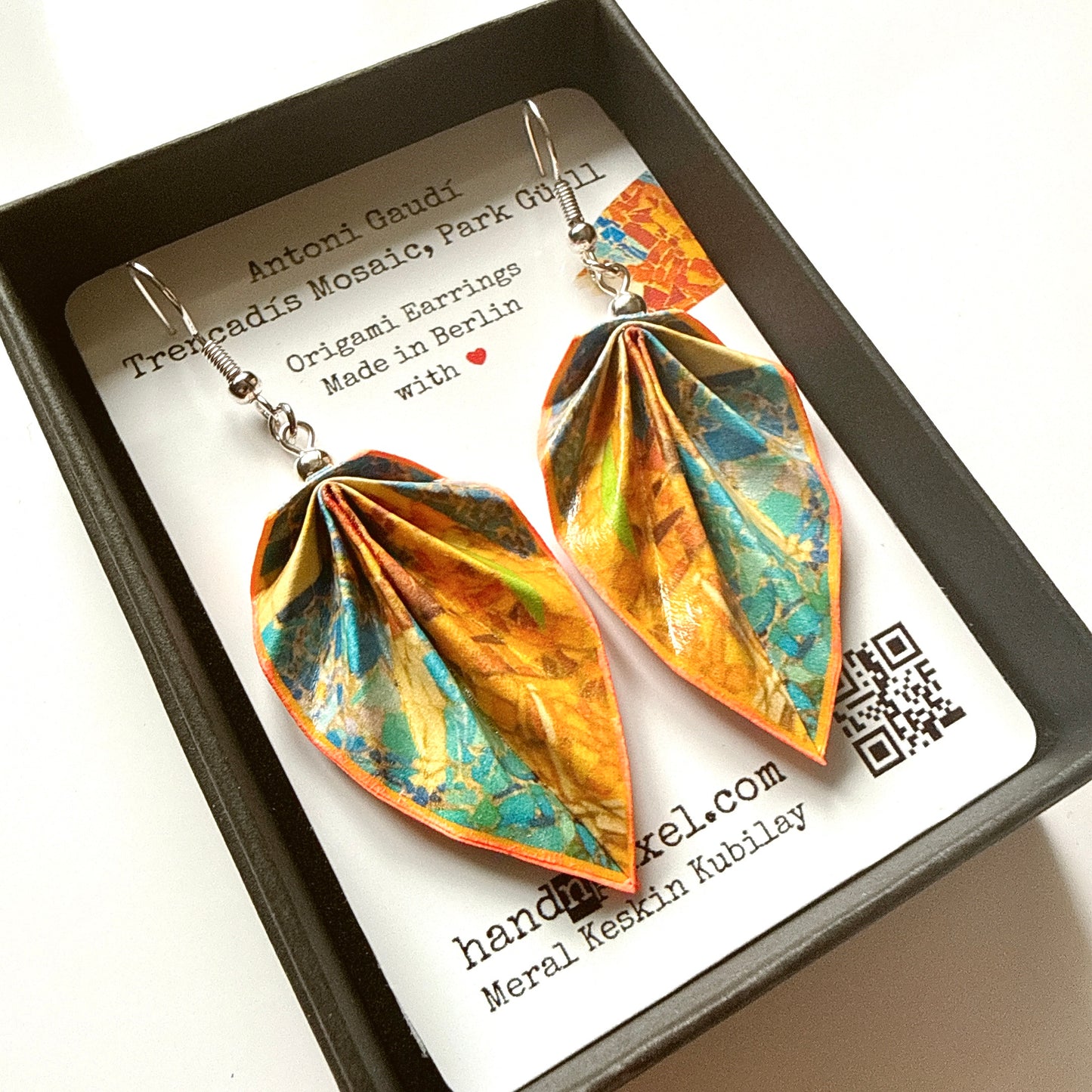 Colorful origami-style earrings in a box with a label