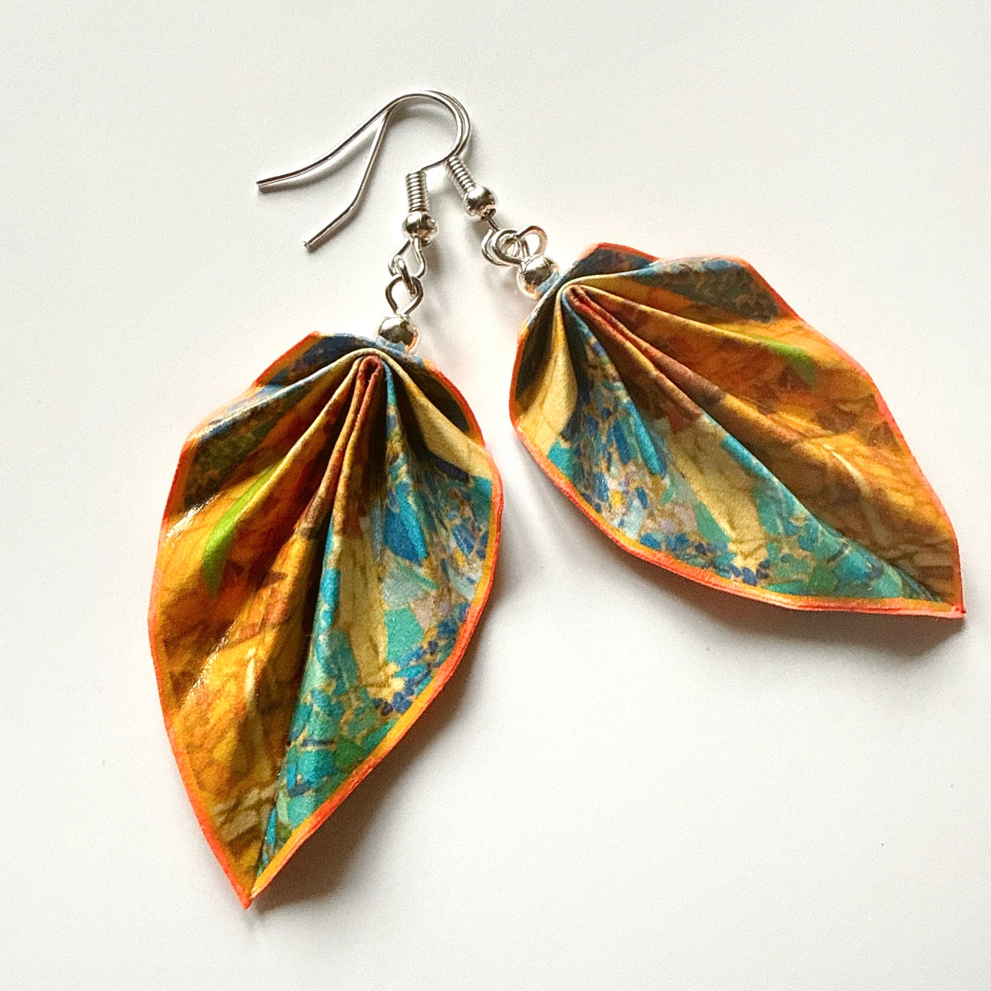 Pair of colorful leaf-shaped earrings on a white background
