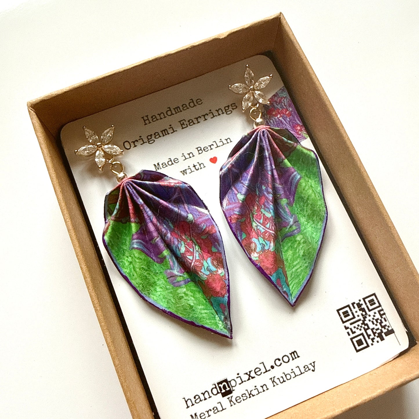 Colorful leaf-shaped earrings in a box with a brand card.