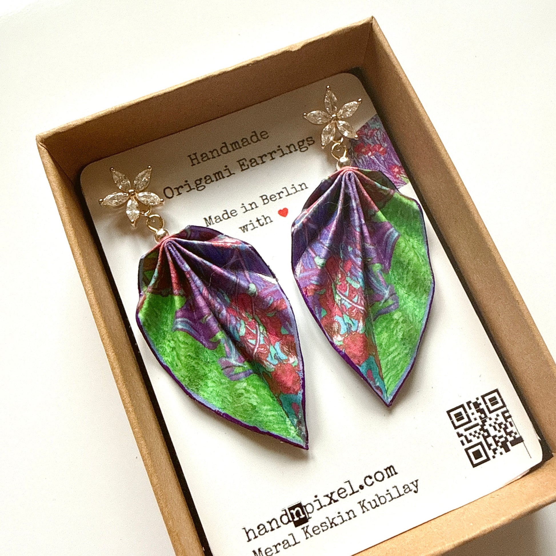 Colorful leaf-shaped earrings in a box with a brand card.