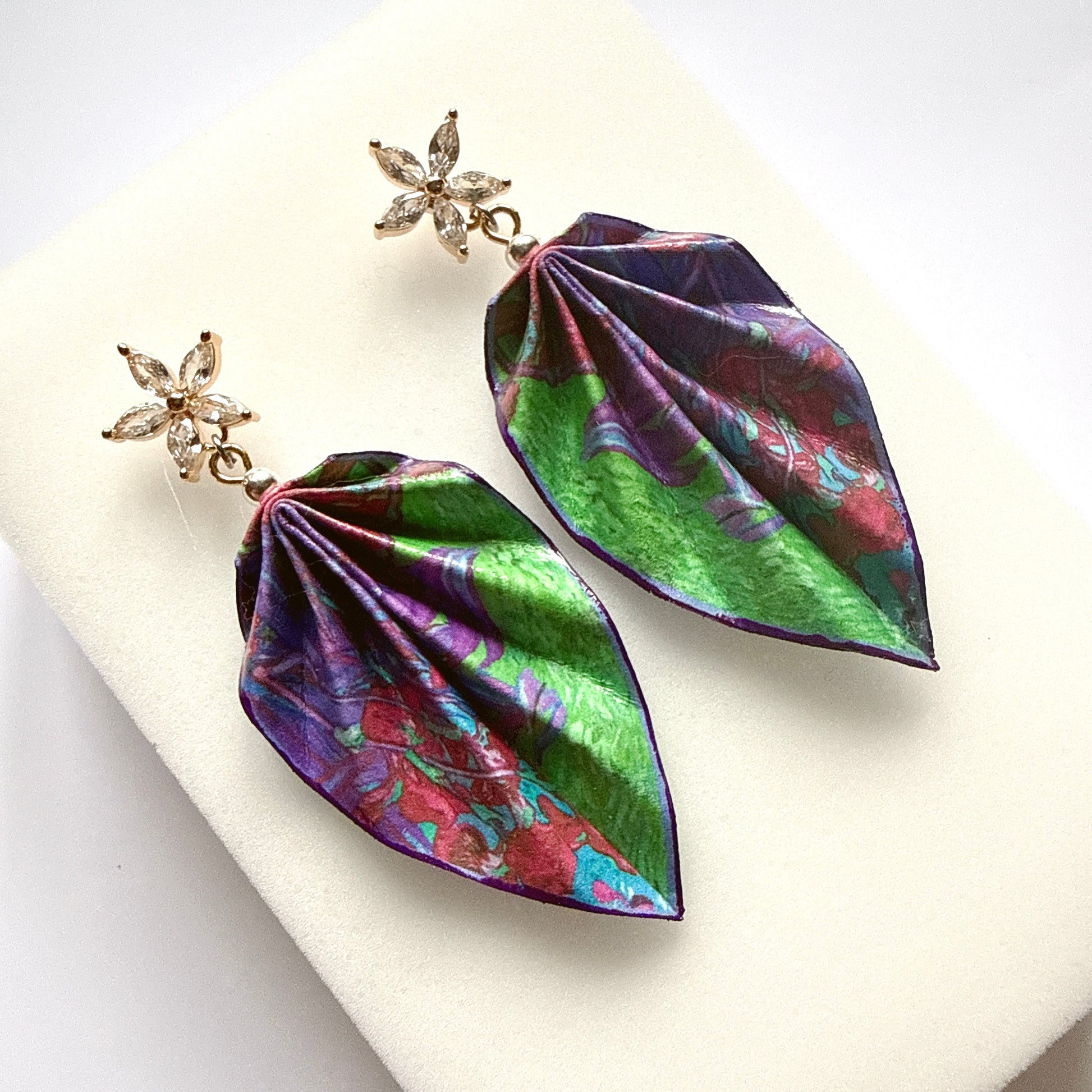 Leaf-shaped earrings with floral design on a white background