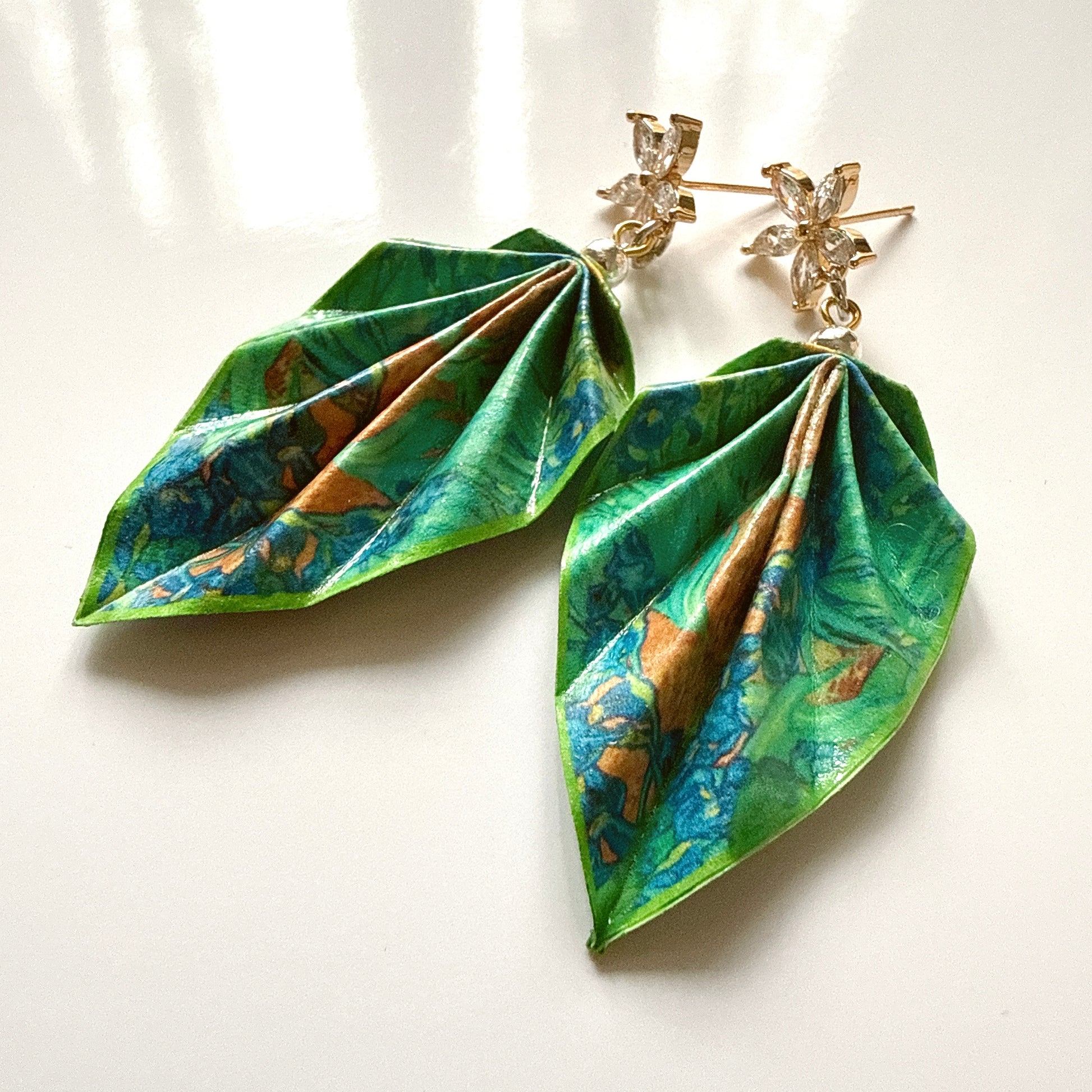 Leaf-shaped earrings with green and blue pattern on a white background