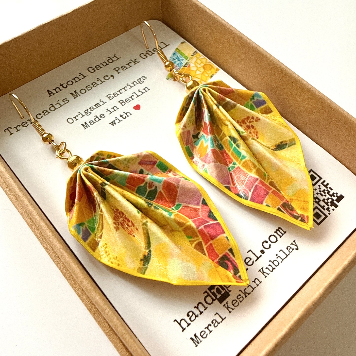 Colorful leaf-shaped earrings in a box with branding information.