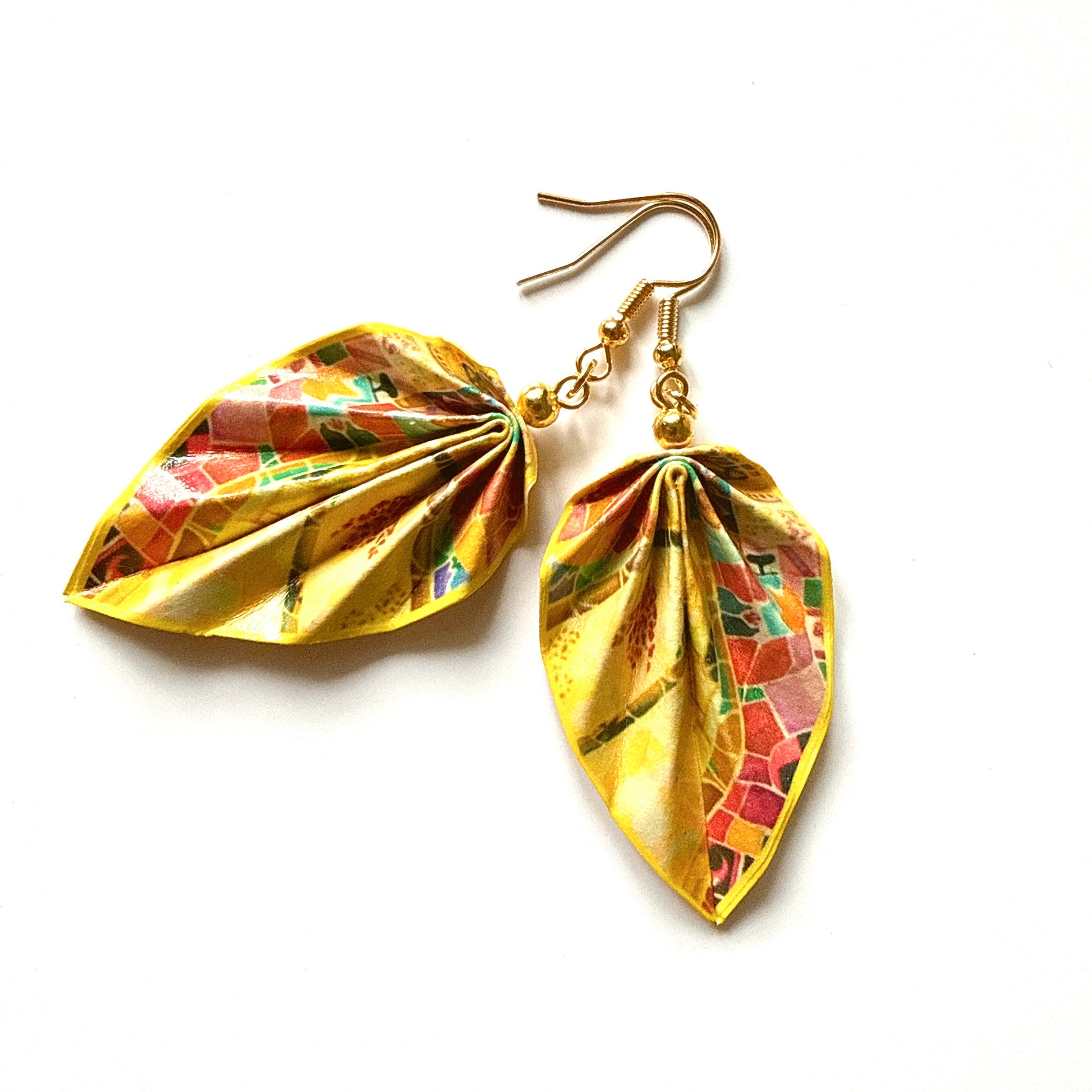 Gold leaf-shaped earrings with mosaic design on a white background