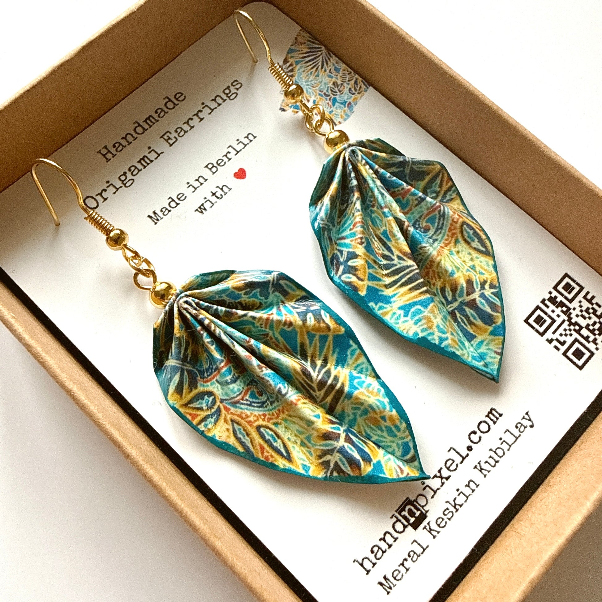 Handmade origami earrings in a box with branding details.