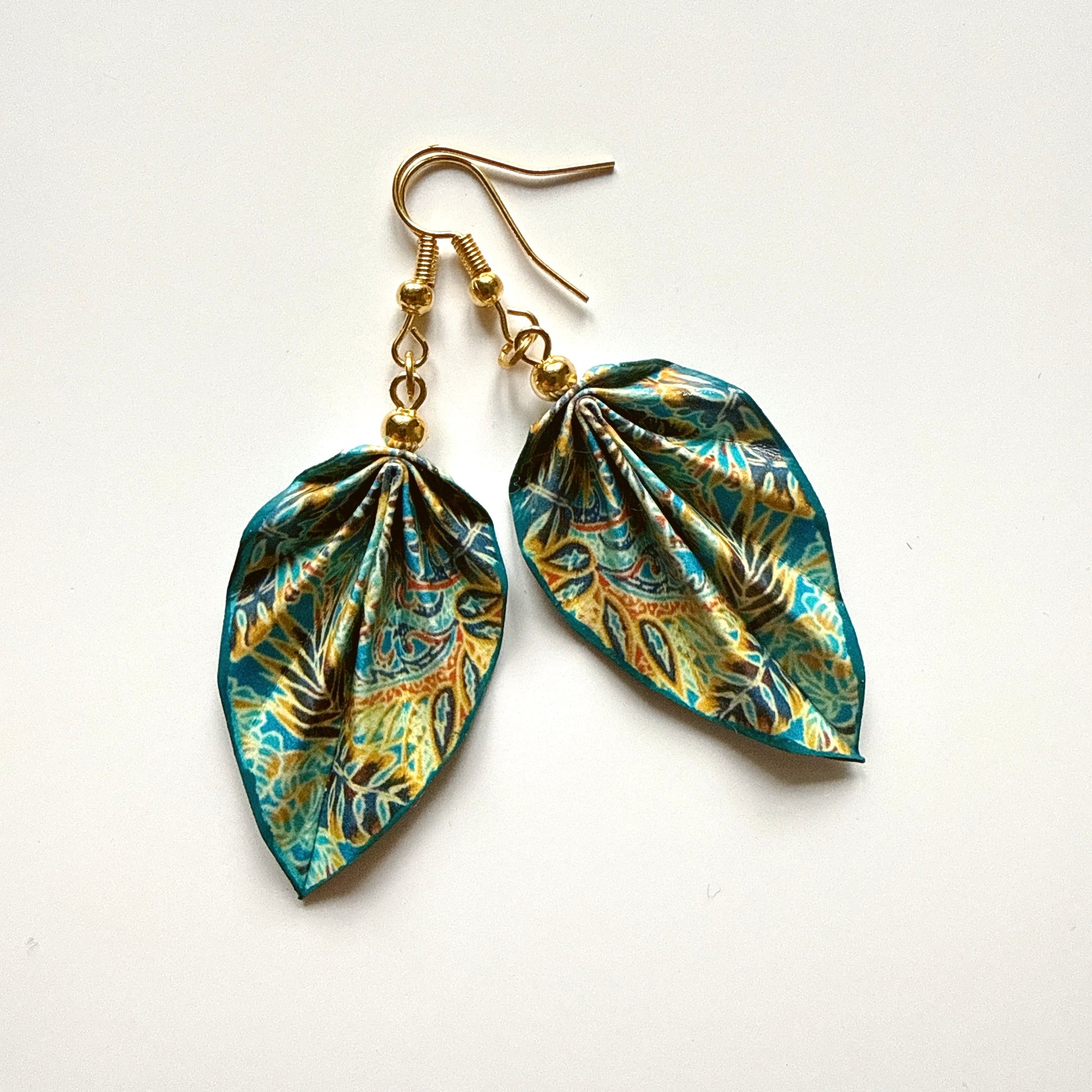 Pair of leaf-shaped earrings with gold hooks on a white background