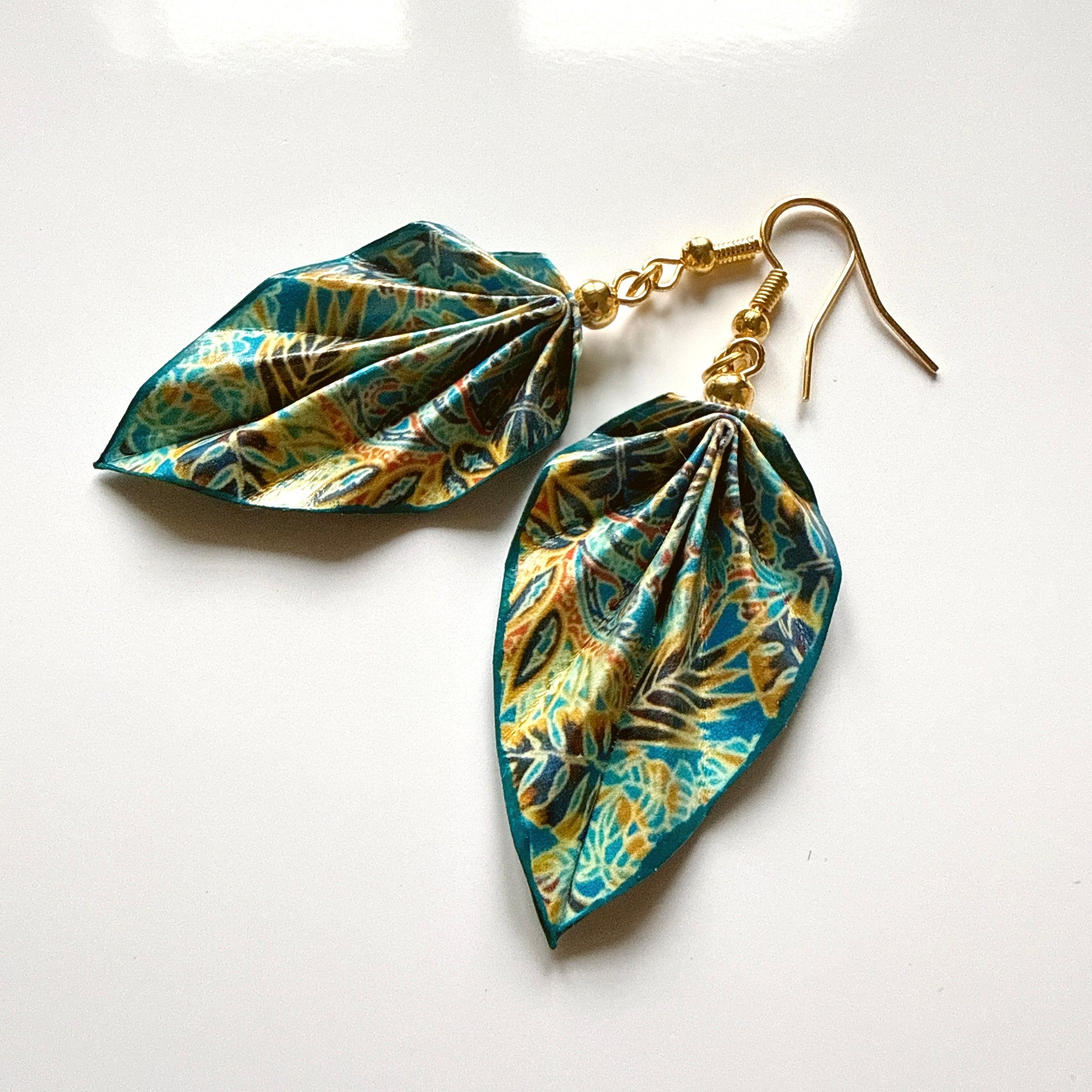 Tropical leaf patterned earrings on a white background