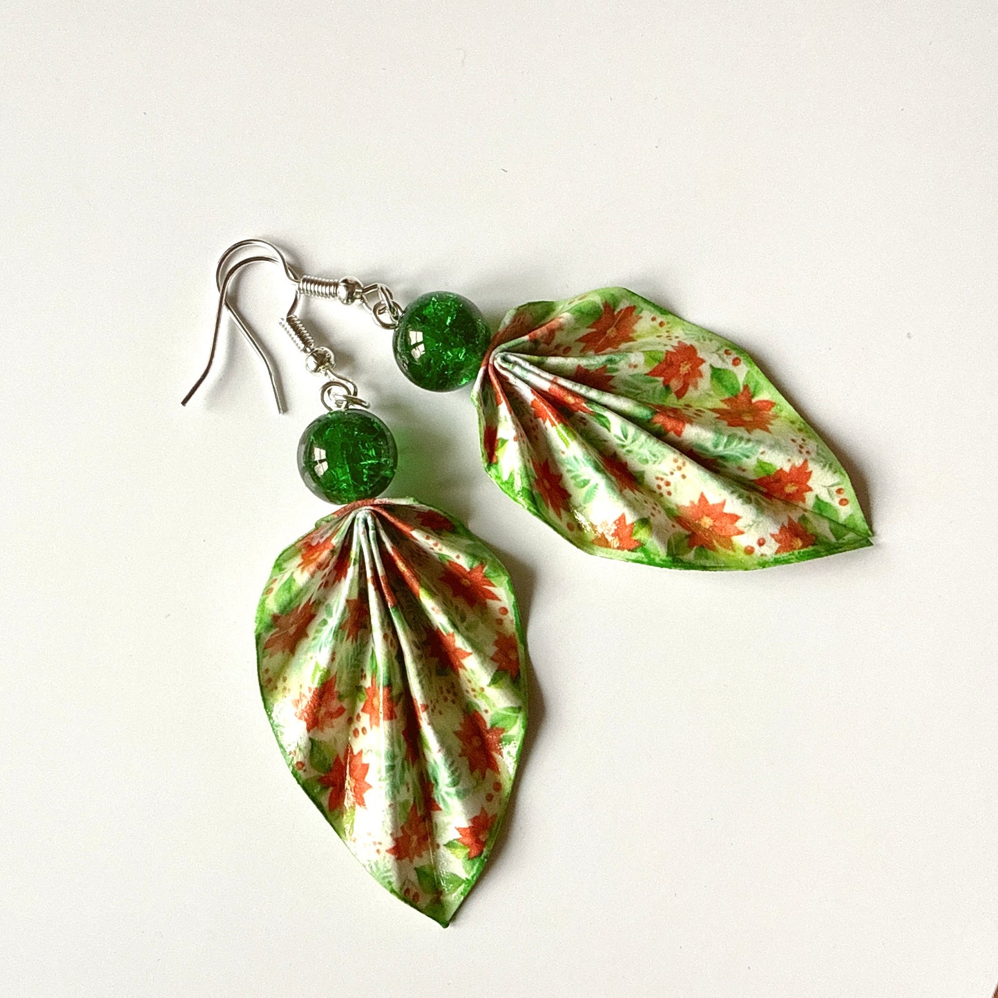 Pair of leaf-shaped earrings with floral pattern on a white background