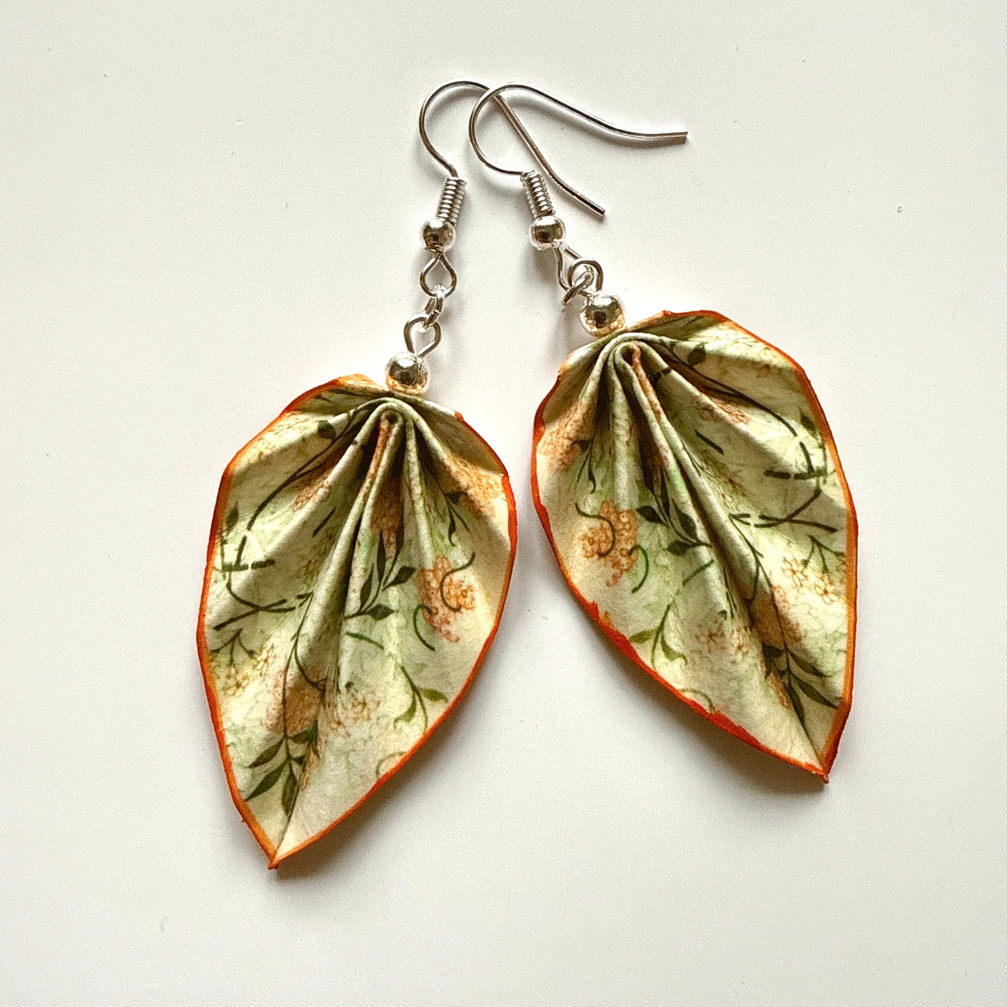 Leaf-shaped earrings with floral design on a white background