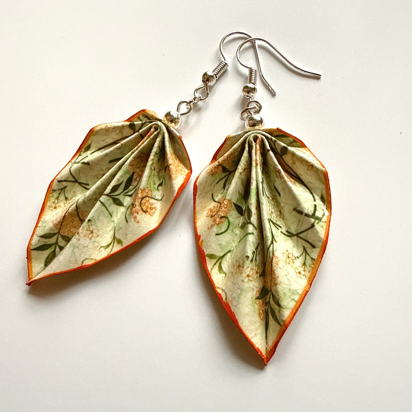 Leaf-shaped earrings with floral pattern on a white background