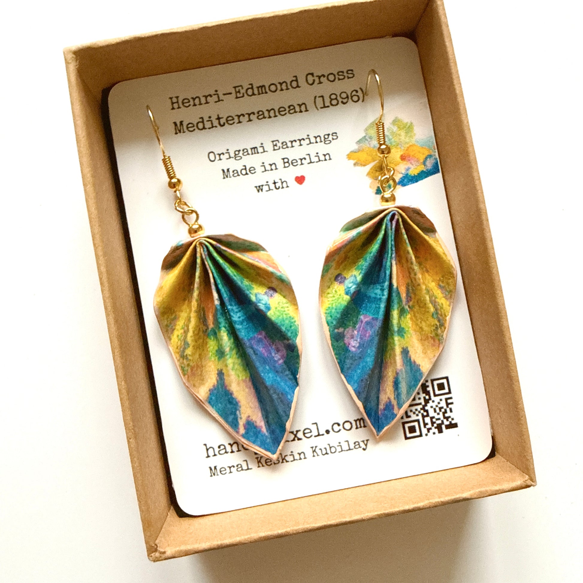 Pair of origami earrings in a box with a card detailing the brand and design.