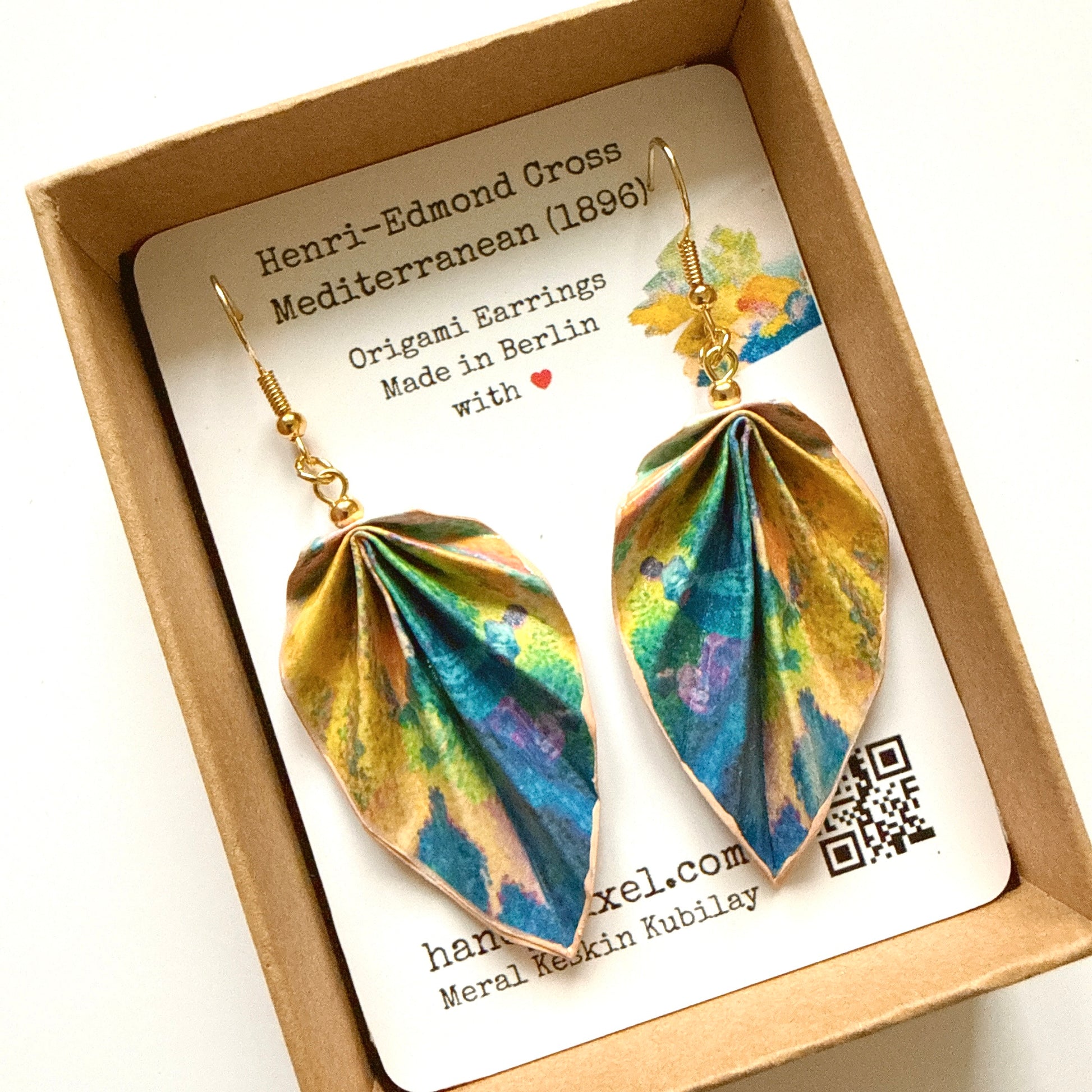 Colorful origami-style earrings in a box with a label