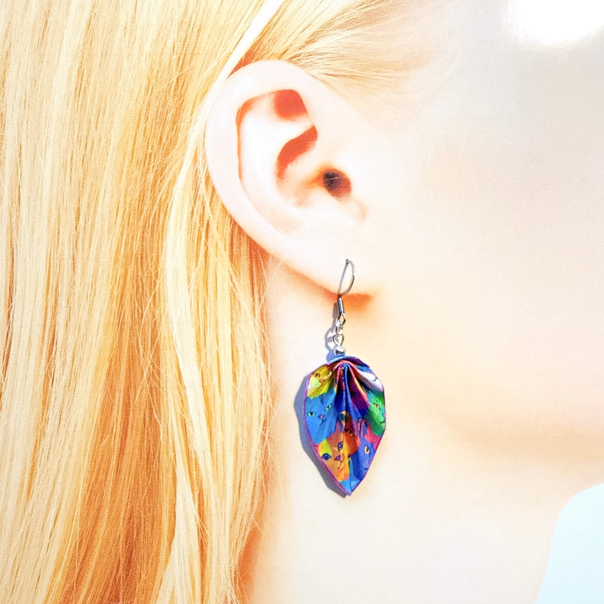 Colorful leaf-shaped earring worn by a person with blonde hair.
