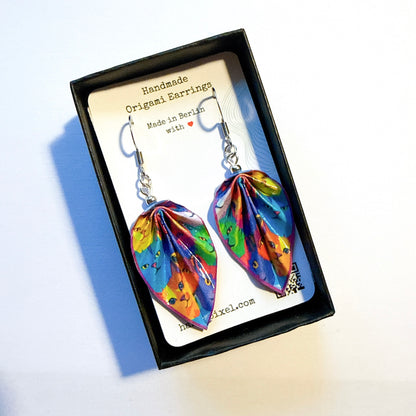 Colorful origami earrings in a black box with a card indicating 'Handmade Origami Earrings Made in Berlin'.