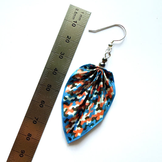 Colorful patterned earring next to a ruler on a white background