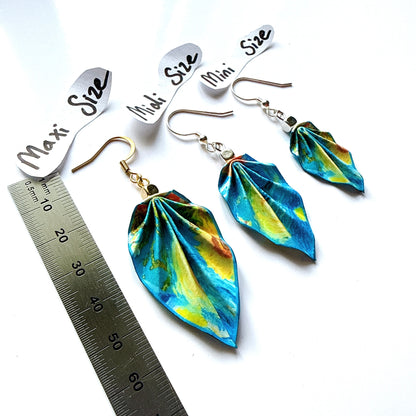 Colorful earrings with size labels and a ruler for scale on a white background