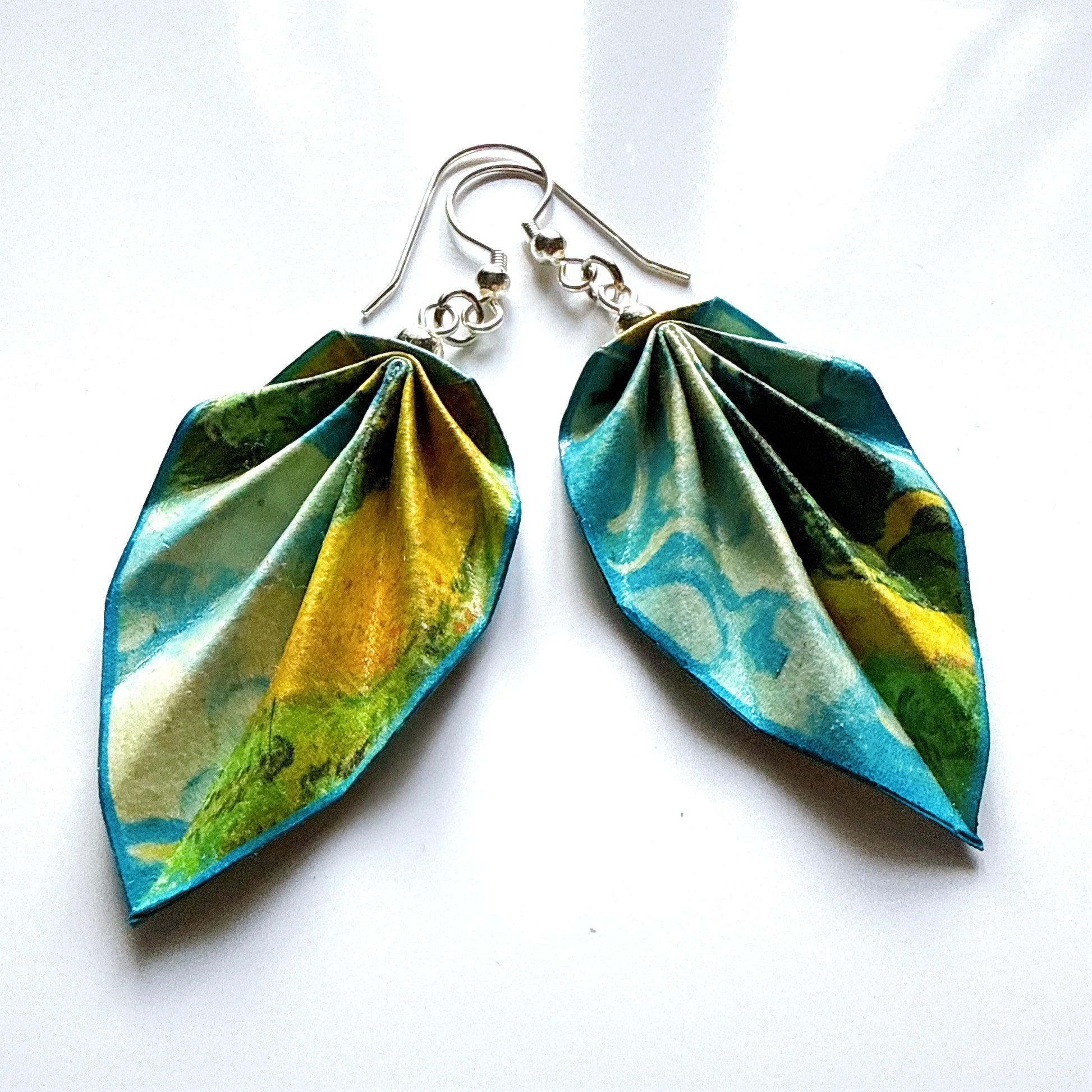 Pair of leaf-shaped earrings with green and yellow design on a white background