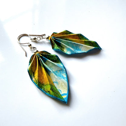 Pair of leaf-shaped earrings with a scenic design on a white background
