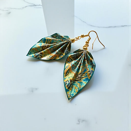 Green leaf-shaped earrings with gold hooks on a white marble surface