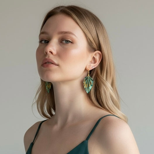 Woman wearing green leaf-shaped earrings against a neutral background