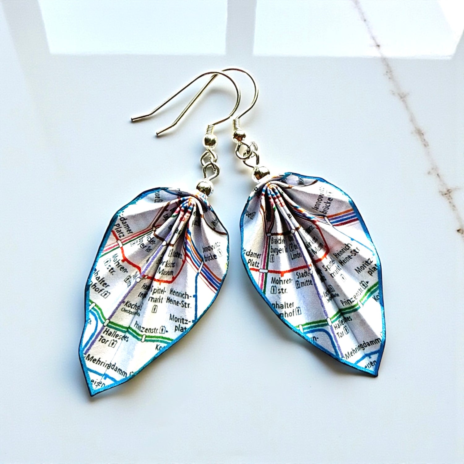 Map-themed earrings on a light background